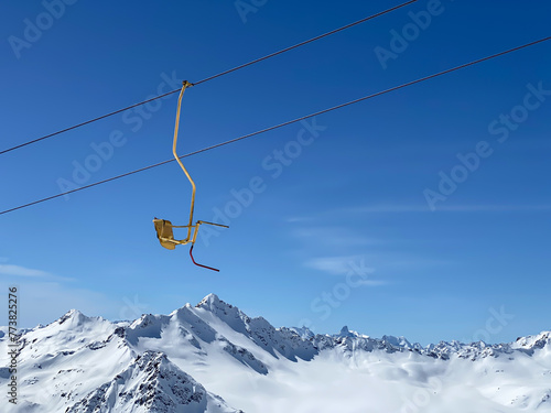 A yellow seat of skiing lift in the mountains on a blue sky background