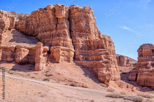 The huge Charyn Canyon in the desert of Kazakhstan. View of the rocks with the adjacent road. Dried yellow grass and the scorching sun on a hot summer day. Geological layers formed by the wind