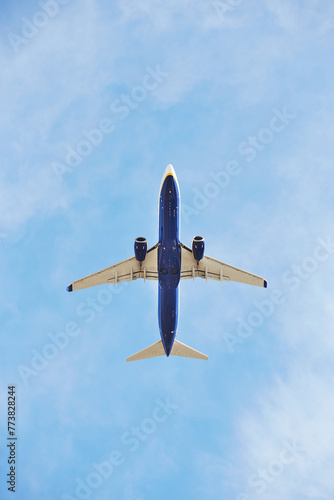 Fotografie Commercial airplane captured from below as it climbs into the vast blue sky, sho