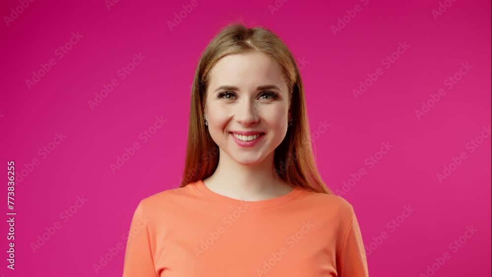 Young Woman Smiling and Blinking Against a Bright Pink Background Young Woman Smiling and Blinking Against a Bright Pink Background