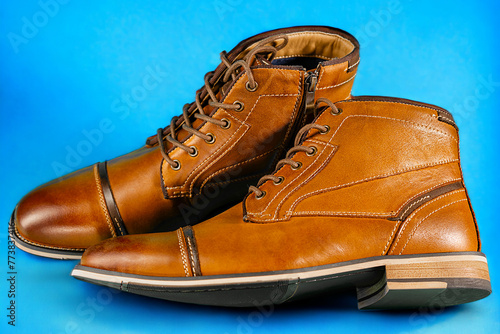 A pair of premium calfskin boots on a blue background. Horizontal shot. photo