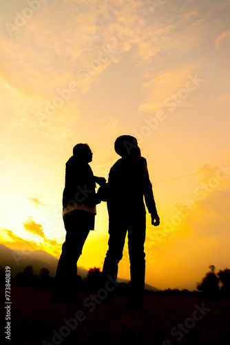 Silhouette of son and father are flying kites, Orange tone in twilight time. © phatthanit
