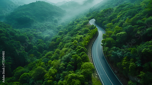 Aerial top view of beautiful curve road between green hills with fog	
