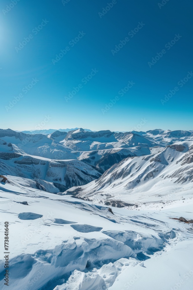 Majestic snowy peaks towering over a frosted valley with clear blue skies in the background.