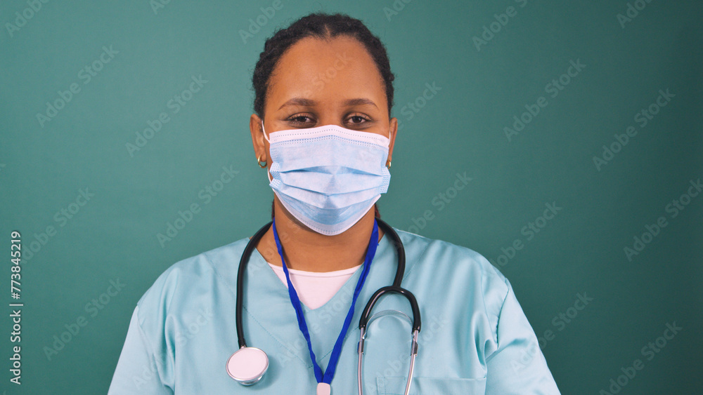 Young Black doctor in scrubs wearing blue surgical face mask, surgery prep Young Black doctor in scrubs wearing blue surgical face mask, surgery prep