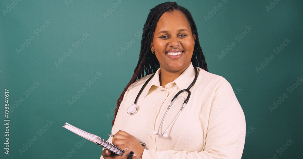 Young Black female doctor making notes on writing pad, smiling Young Black female doctor making notes on writing pad, smiling