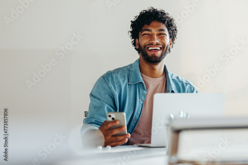 Happy young businessman working with technology for communication and connectivity in his office
