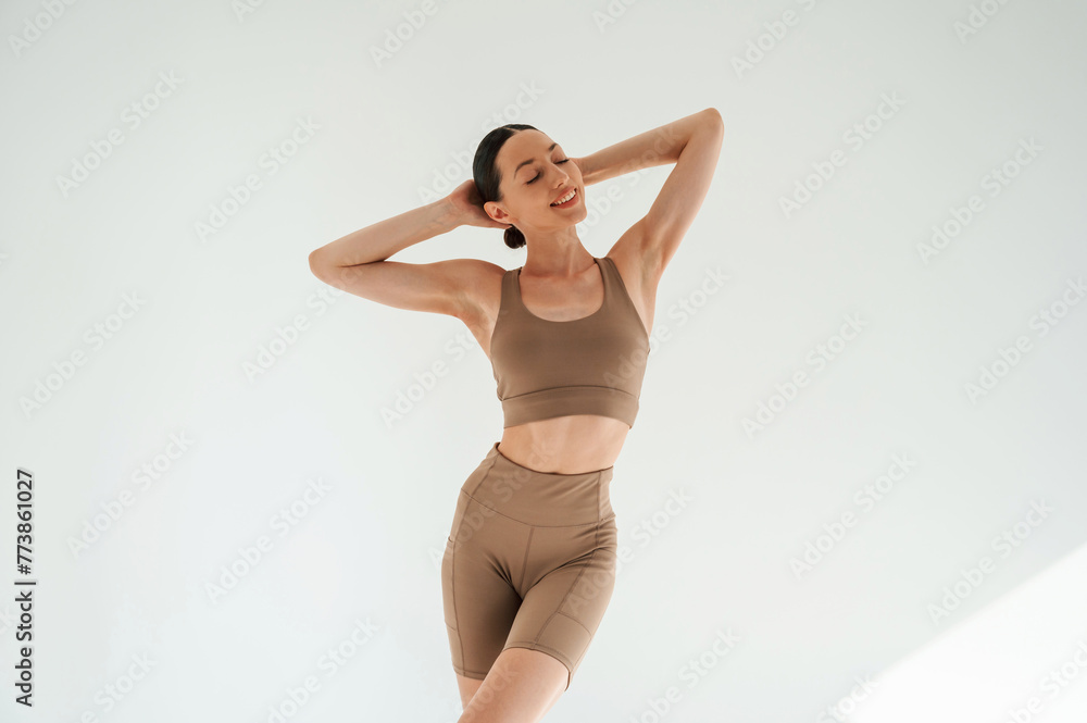 Woman in fitness clothes is standing against white background - obrazy, fototapety, plakaty 