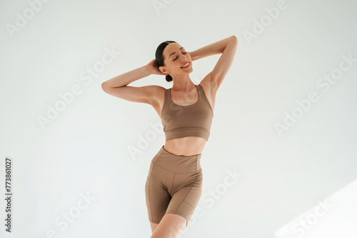 Woman in fitness clothes is standing against white background
