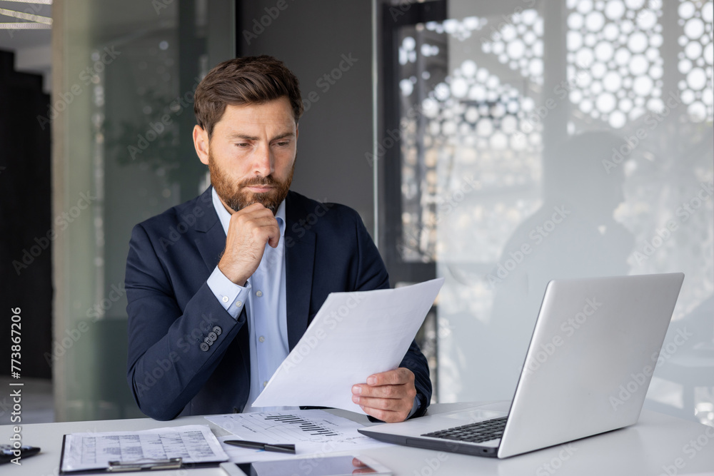 Serious accountant analyzing financial documents at the office Serious accountant analyzing financial documents at the office