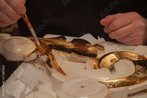 The artist craftsman gilds the ornament with real gold. Goldsmith. Hands and brush