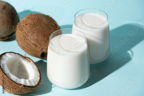 Coconut milk in a glasses among coconuts on a blue background