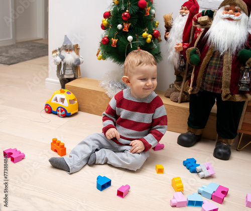 A little boy is sitting on a hardwood and playing with toys.