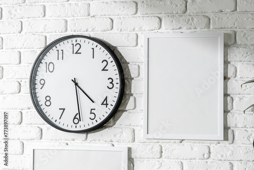 Minimalist White Wall Decor Featuring a Clock and Blank Photo Frames