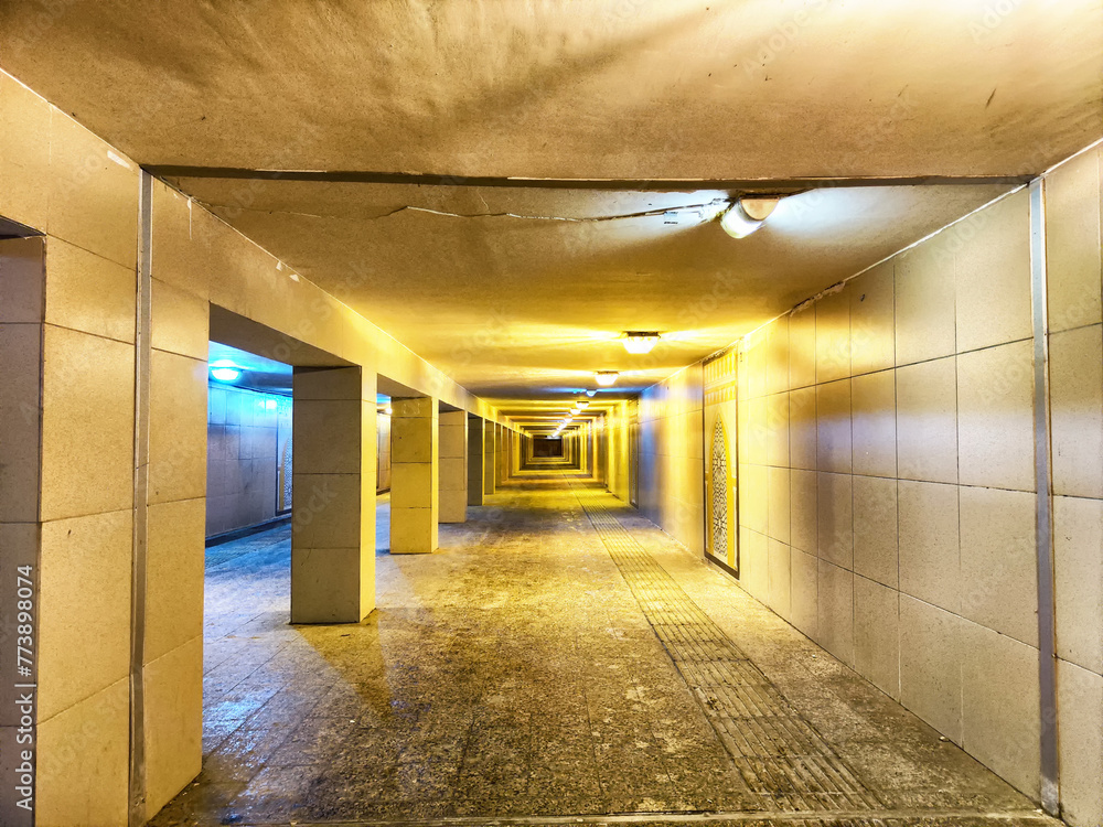 Illuminated Underground Pedestrian Tunnel by Night. A well lit tunnel with columns, leading into the distance Illuminated Underground Pedestrian Tunnel by Night. A well lit tunnel with columns, leading into the distance