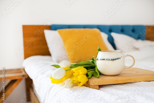 Coffee cup and bouquet of yellow tulips in bed. Concept of holiday, birthday, Women Day. Feminine flat lay. Breakfast in bed. Good morning. still life. Romantic background