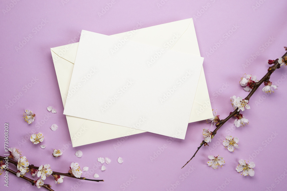 Blank greeting card, envelope on a purple background with blossoming tree branches. Feminine still life composition. Flat lay, top view, copy space. Mock up. Blank greeting card, envelope on a purple background with blossoming tree branches. Feminine still life composition. Flat lay, top view, copy space. Mock up.