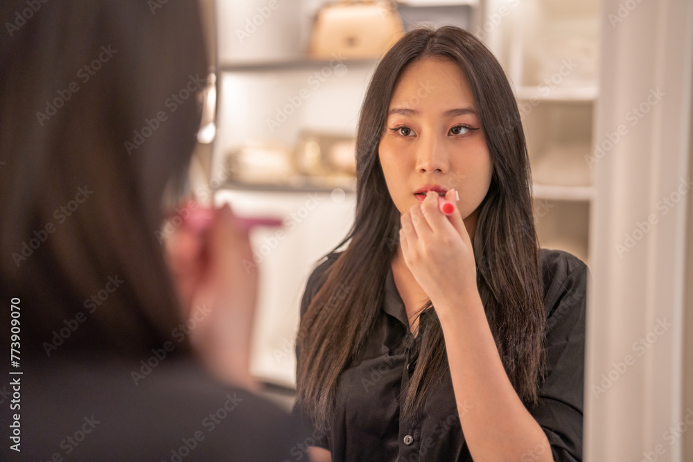 Smiling beautiful asian woman fresh healthy skin looking on mirror and enjoying applying skincare lips with red lipstick at home.facial beauty and cosmetic concept Smiling beautiful asian woman fresh healthy skin looking on mirror and enjoying applying skincare lips with red lipstick at home.facial beauty and cosmetic concept