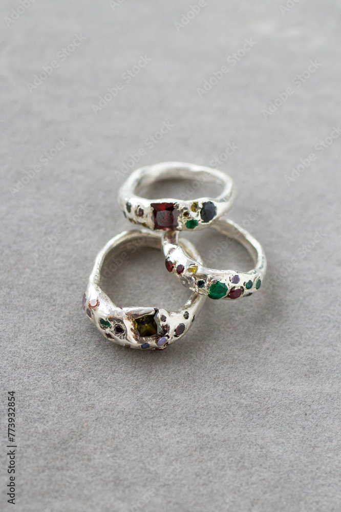 Three silver rings with natural gemstones on a gray background, highlighting their beauty. Elegant and sophisticated, perfect for special occasions.