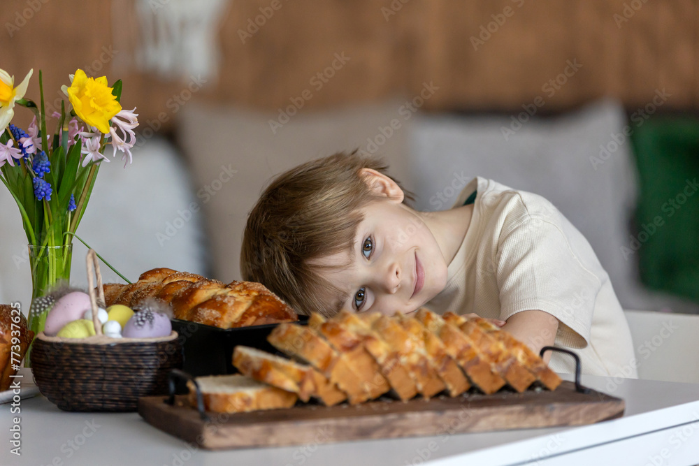 Cute preschool child, boy, holding sweet brioche bun for Easter, traditional swee bread baked with almonds, nuts and sugar Cute preschool child, boy, holding sweet brioche bun for Easter, traditional swee bread baked with almonds, nuts and sugar