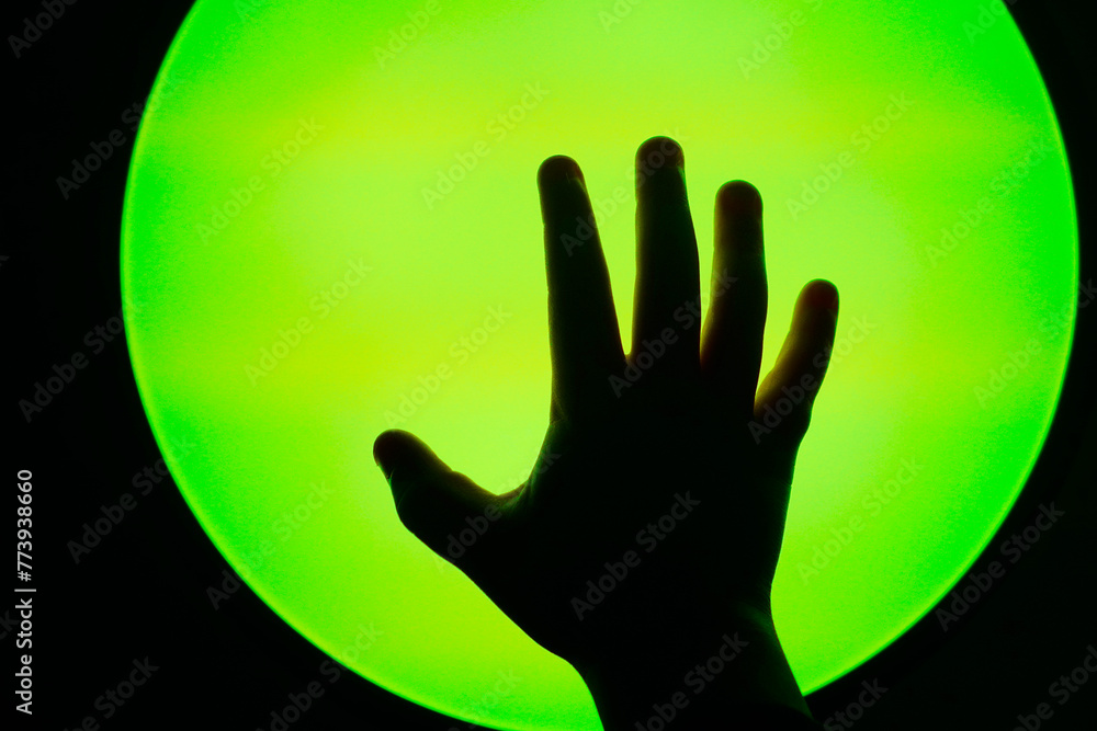 The shape of a hand reaching towards a colored light