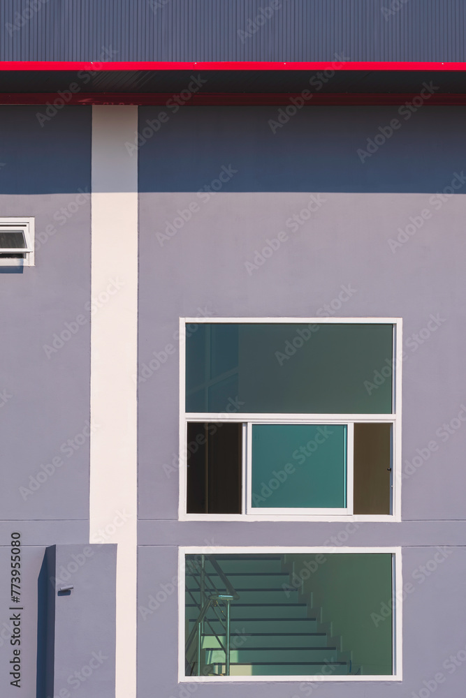 Glass windows on gray cement wall near the stairway inside of modern industrial office building in vertical frame Glass windows on gray cement wall near the stairway inside of modern industrial office building in vertical frame