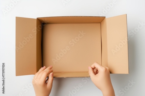 Top view to female hands opening empty brown cardboard box on white background. Mockup parcel box. Packaging, shopping, delivery concept © ERiK