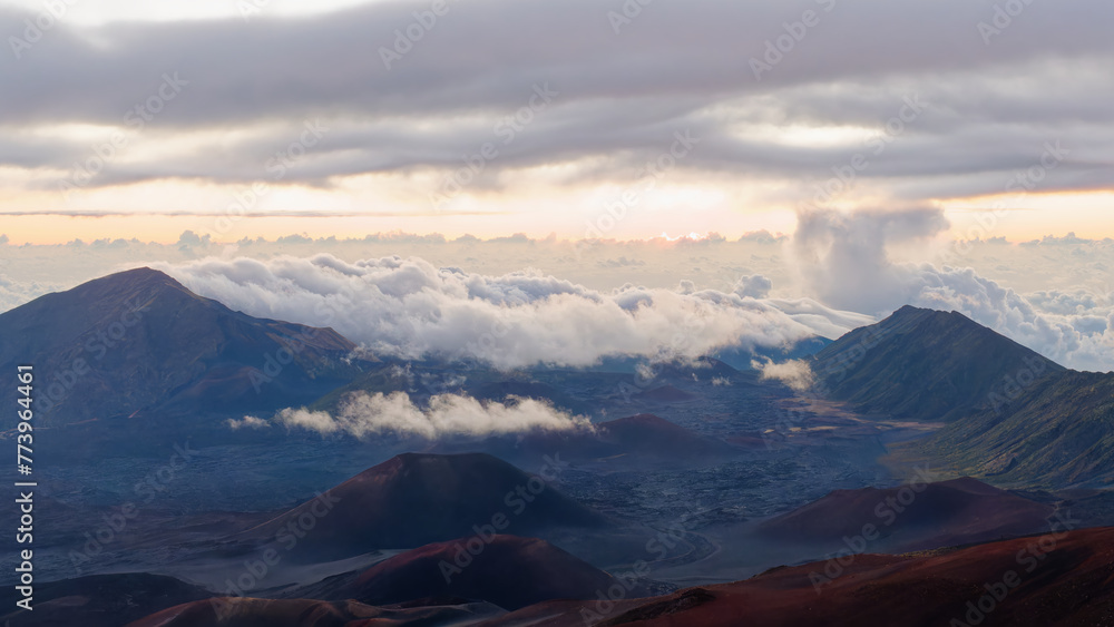 Tranquil view of the amazing sunrise through the clouds over Haleakala volcano summit at Haleakala National Park on the island of Maui, Hawaii, USA Tranquil view of the amazing sunrise through the clouds over Haleakala volcano summit at Haleakala National Park on the island of Maui, Hawaii, USA