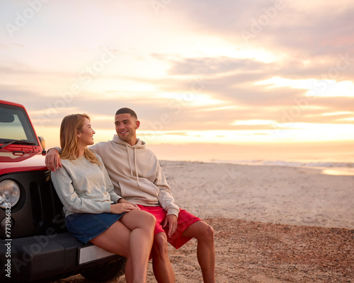 Young Couple Standing Chatting By Car At Beach Watching Sunrise Together © Monkey Business