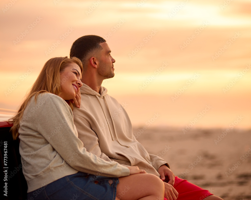 Loving Young Couple Sitting On Fender Of Car At Beach Watching Sunrise Together Loving Young Couple Sitting On Fender Of Car At Beach Watching Sunrise Together
