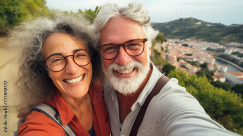 Couple of gray haired mature smiling people travel and taking selfie portrait on phone. Wonderful cheerful man and woman. Active retirees are enjoying life. A man with a gray beard and a woman, travel