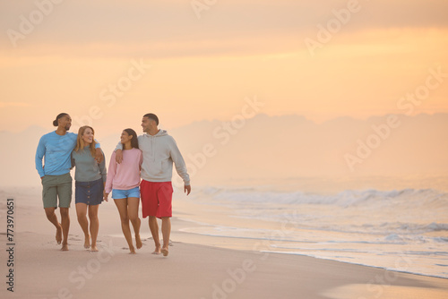 Hugging Couple With Friends In Casual Clothing On Vacation Walking Along Beach Shoreline At Dawn