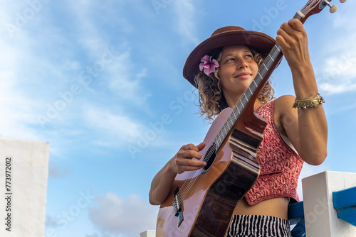 Female musician playing guitar outdoors in urban setting photo