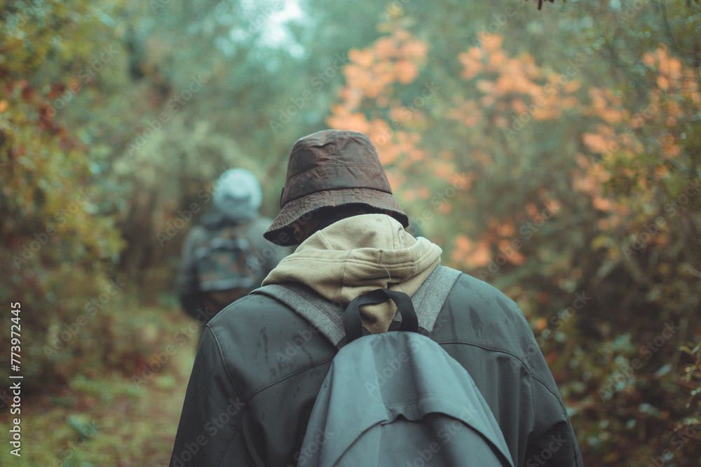 Person walking in the woods with a backpack and a jacket. Person walking in the woods with a backpack and a jacket.