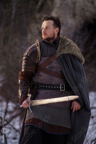 Medieval knight with sword in armor as style Game of Thrones in winter forest