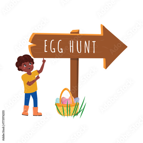 Black boy pointing up on the Egg hunt shield and on the floor standing a basket filled with painted eggs