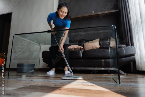 cleaning service housekeeper women swipe floor in living room. House cleaning service concept photo