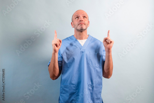 Portrait of a female physiotherapist in light blue dress pointing up.