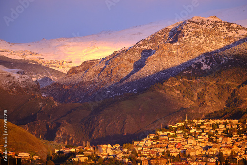 Views of Sierra Nevada from Granada during the golden hour at sunset with the peaks full of snow.