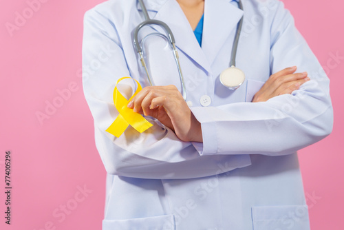 Medical doctor holding yellow ribbon isolated on pink background, Yellow September, Suicide prevention day, Childhood, Sarcoma, bone and bladder cancer Awareness month.