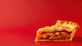 A slice of apple pie with a flaky crust on red background, showcasing the layered fruit filling