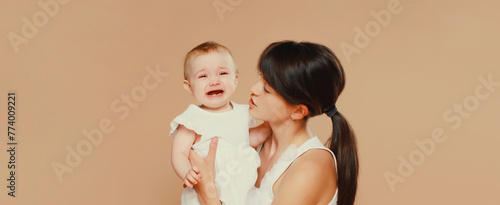 young mother holding crying baby on studio background © rohappy