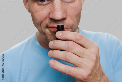 Young man having long-term covid effect and trying to sense smell of essential oil. Scent exploration: Man contemplates smell, evoking memories of loss
