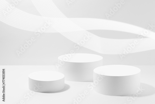 Abstract white scene mockup - three round white cylinder podiums, with glowing light lines. Template for presentation cosmetic products, goods, advertising, design, display, showing in spring style.