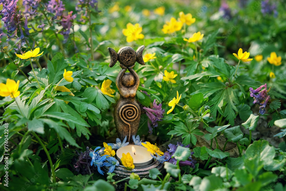 amulet of Triple Goddess with candle close up on floral meadow, natural ...