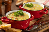 Bowls of split pea soup with ham and carrots garnished with parsley