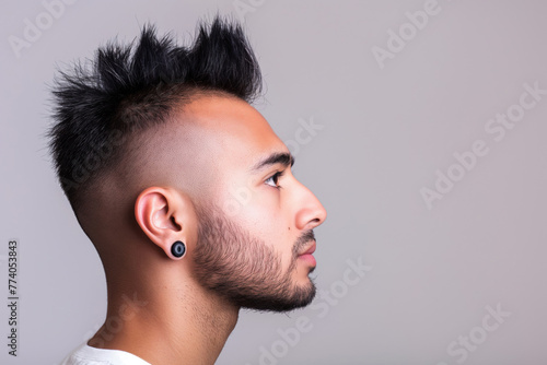 Side profile of a man sporting a trendy mohawk haircut, detailed against a neutral background photo