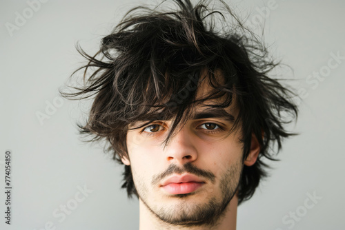 Trendy young adult man with a modern shaggy hairstyle and unkempt look in a close-up portrait, showcasing his stylish and individual fashion sense in a casual, natural, and contemporary way photo