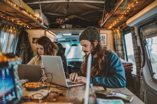 A young couple focused on their laptops inside a cozy camper van in nature