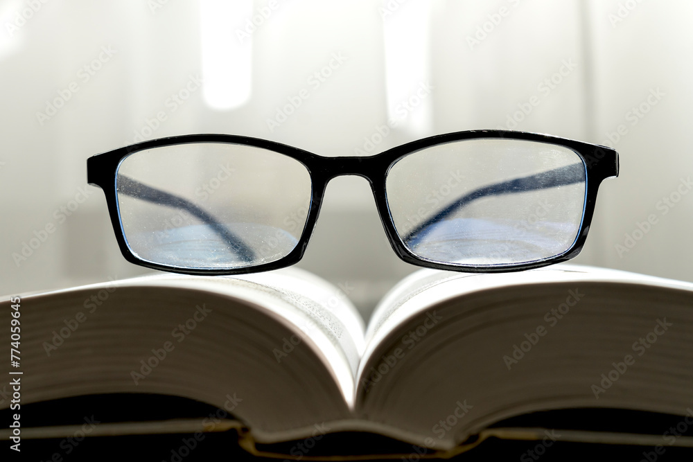 Close-up photo of eyeglasses on the book in education and reading book concept Close-up photo of eyeglasses on the book in education and reading book concept